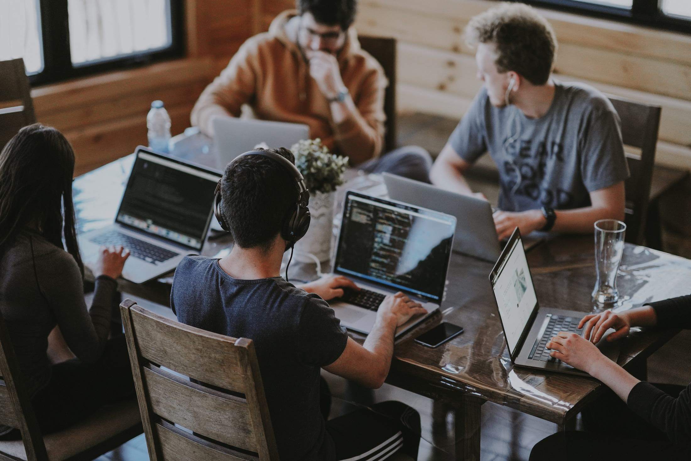 when-to-scale-product-team Team sitting around a table with laptops out. When should you scale the product team?